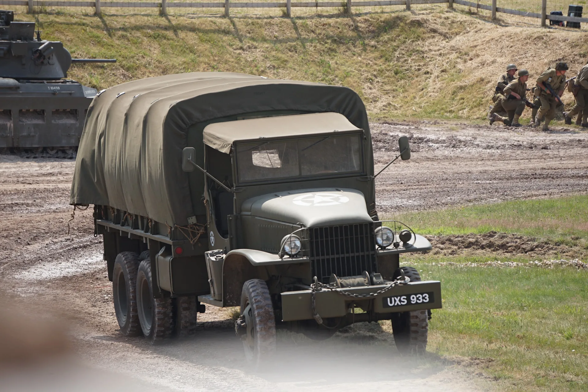 A wartime GMC truck under canvas, registration UXS 933, crossing the arena.