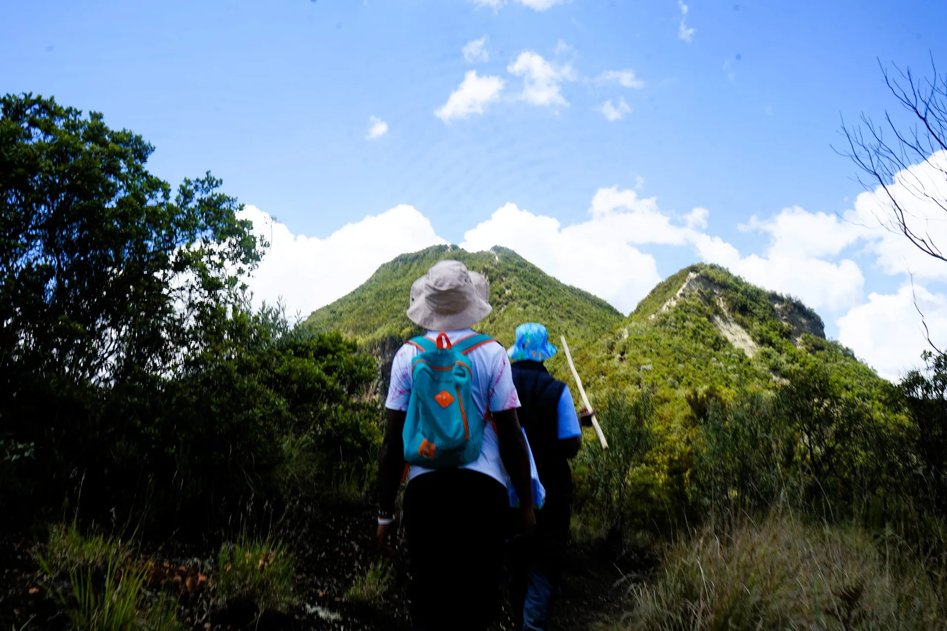 Two hikers walking a ridge path toward the Longonot summit.