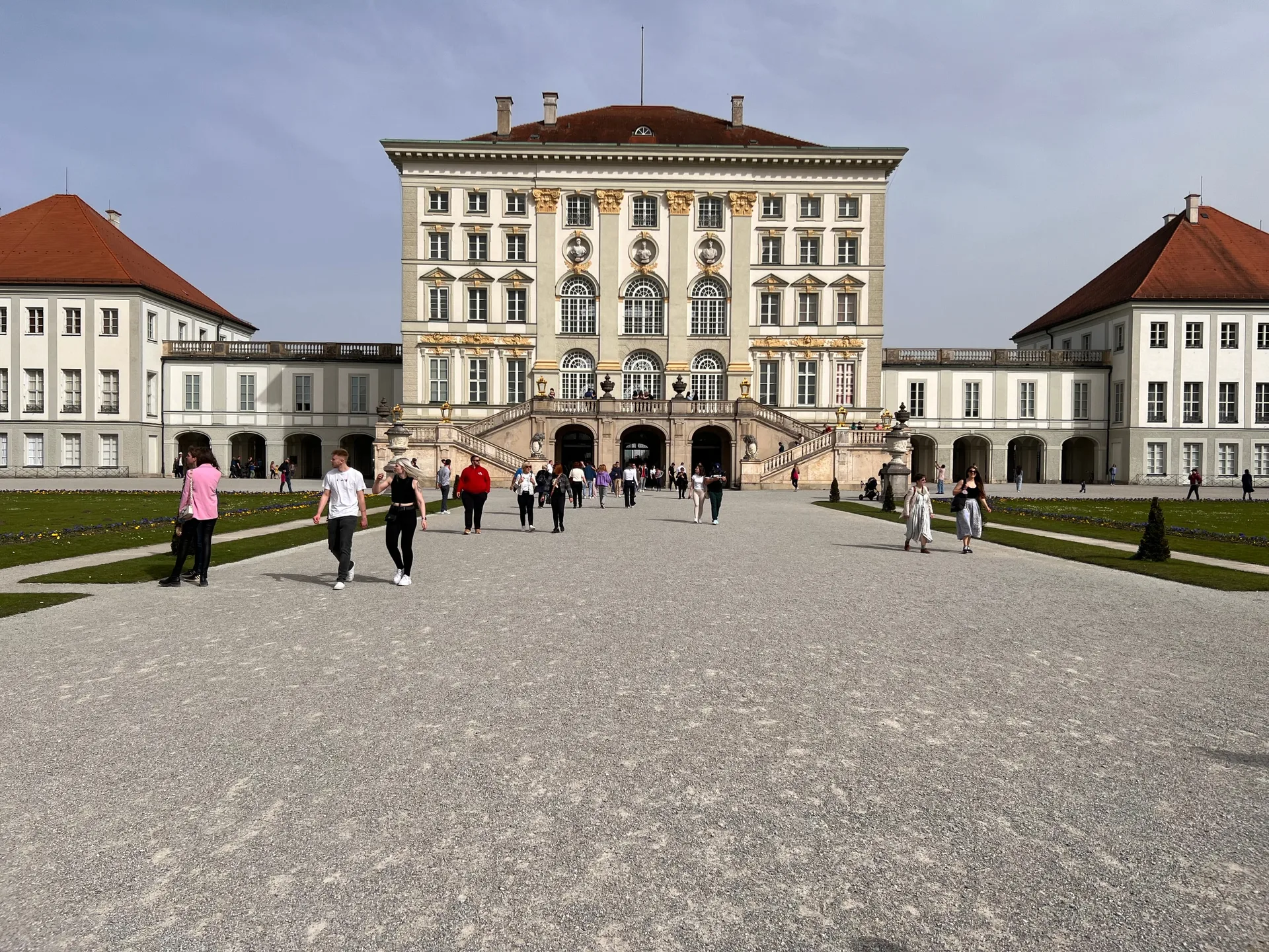 Nymphenburg Palace across its forecourt, visitors small on the gravel.